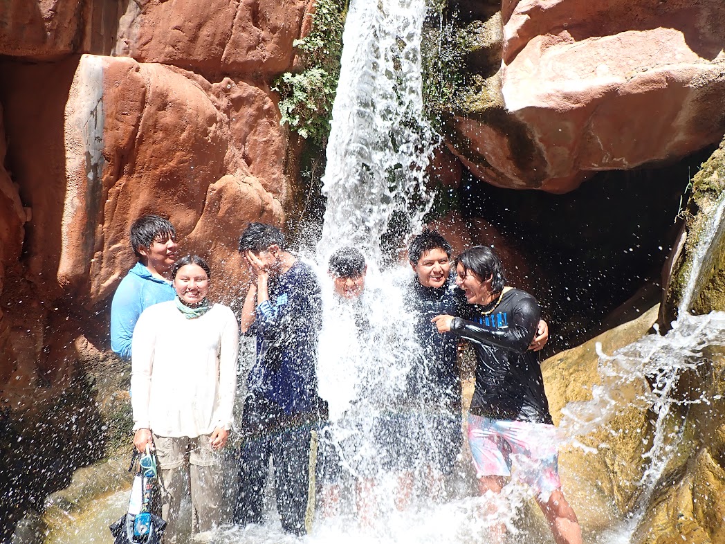 a group of kids stand under a waterfall